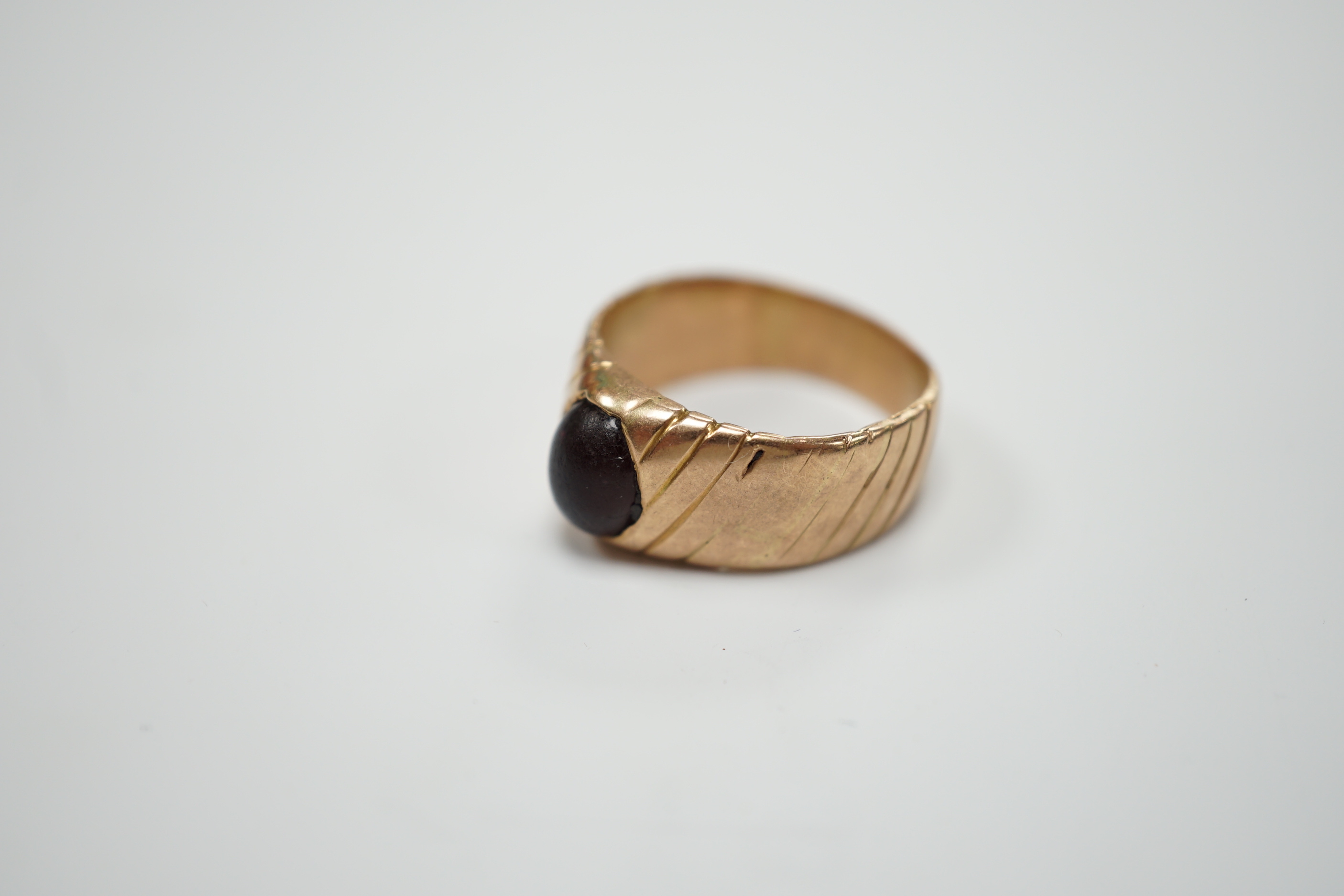 An antique engraved yellow metal and cabochon red paste set ring, size Q, gross weight 5.8 grams.